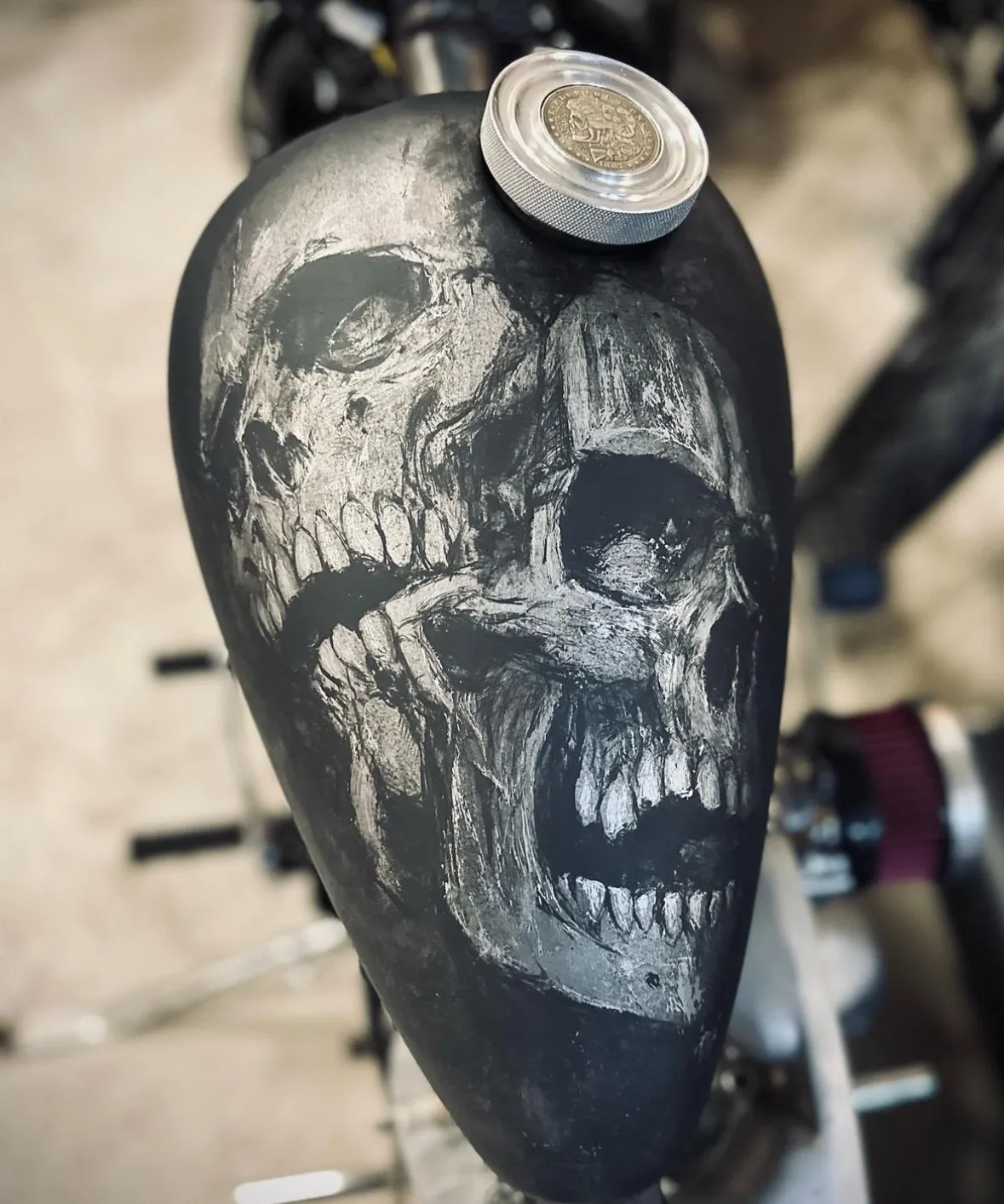 Hand-painted double skull on a matte black motorcycle tank